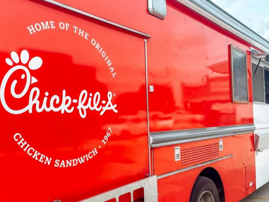 A bright red Chick-fil-A food truck with the logo &ldquo;Home of the Original Chick-fil-A Chicken Sandwich&rdquo; on the side, parked outdoors.